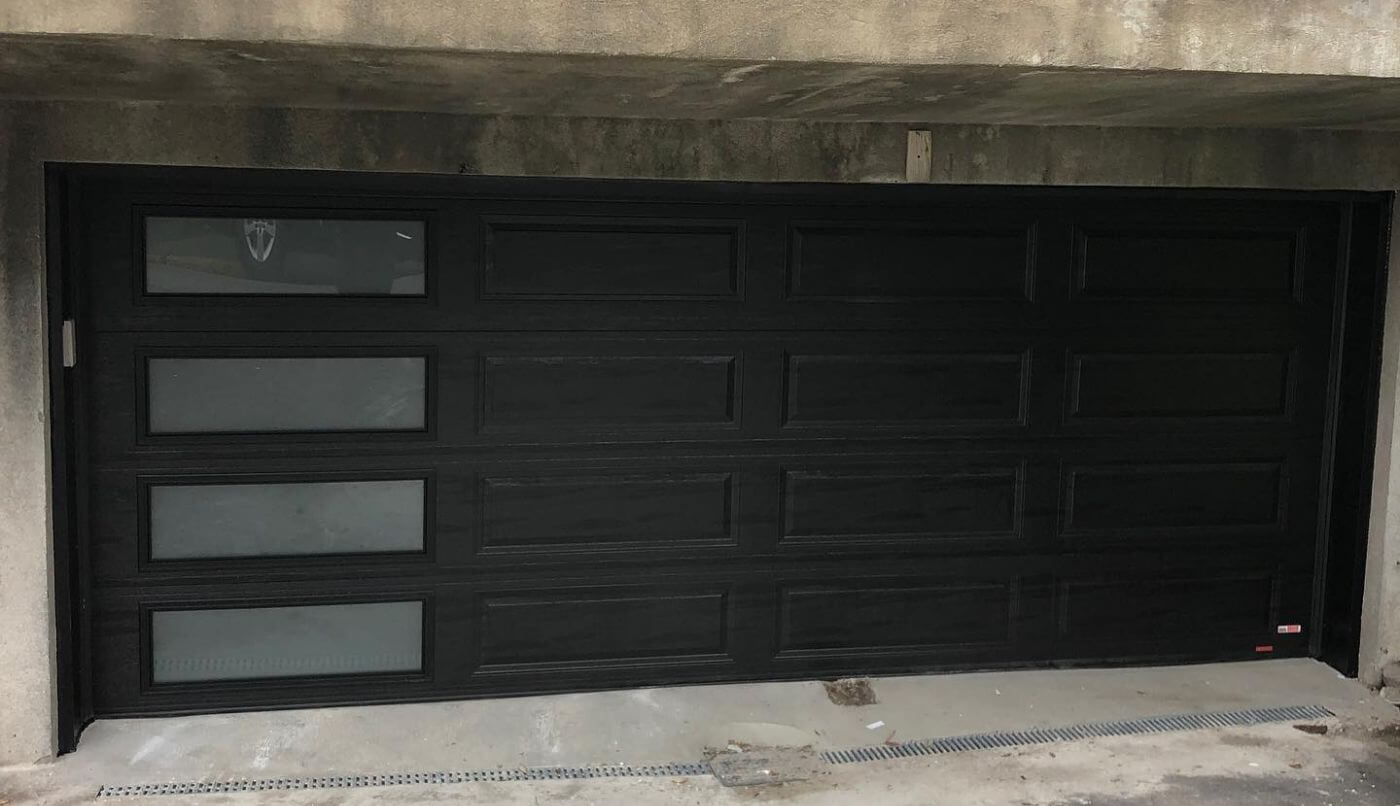 Une porte de garage noire avec des fenêtres, offrant un design moderne et élégant.