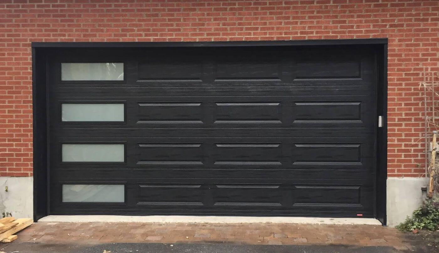 Porte de garage noire avec des fenêtres, ajoutant une touche contemporaine à l'extérieur.