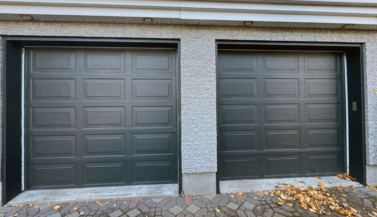 Deux portes de garage noires sur le flanc d'un bâtiment.