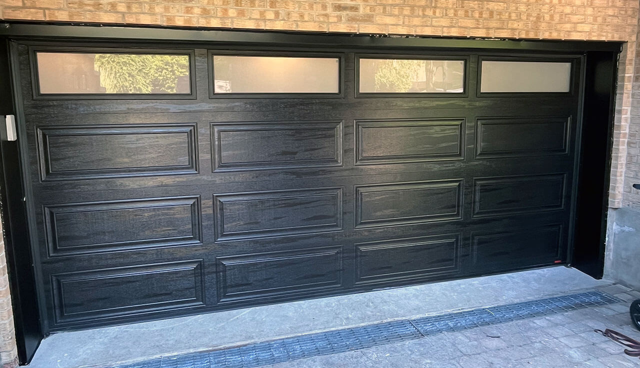 Porte de garage noire avec fenêtres, offrant un design classique et élégant. 