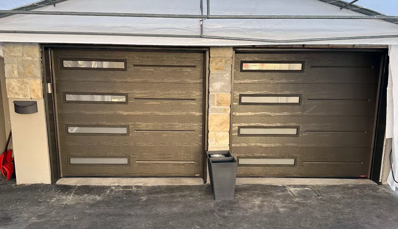 Deux portes de garage spacieuses, dotées de fenêtres étroites, permettant de voir à travers.