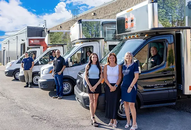 Équipe de travail souriante devant leurs camions de service