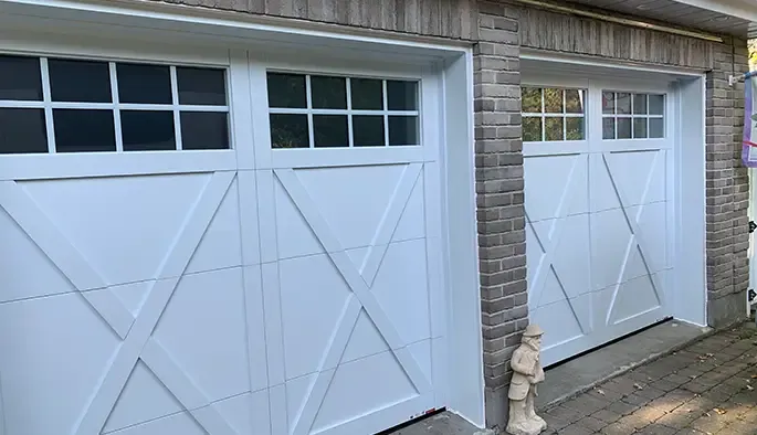 Deux portes de garage blanches avec des traverses encadrées par des murs en briques.